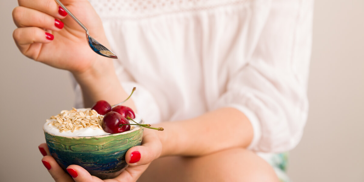 Person holding bowl of granola and cherries.