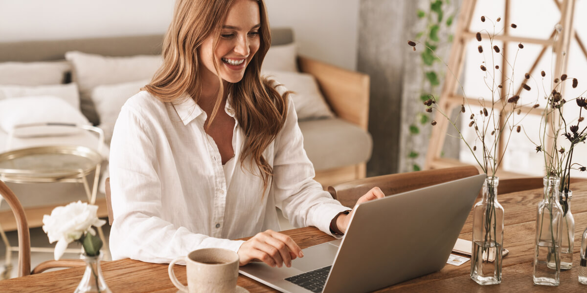 Woman smiling working on laptop at home.